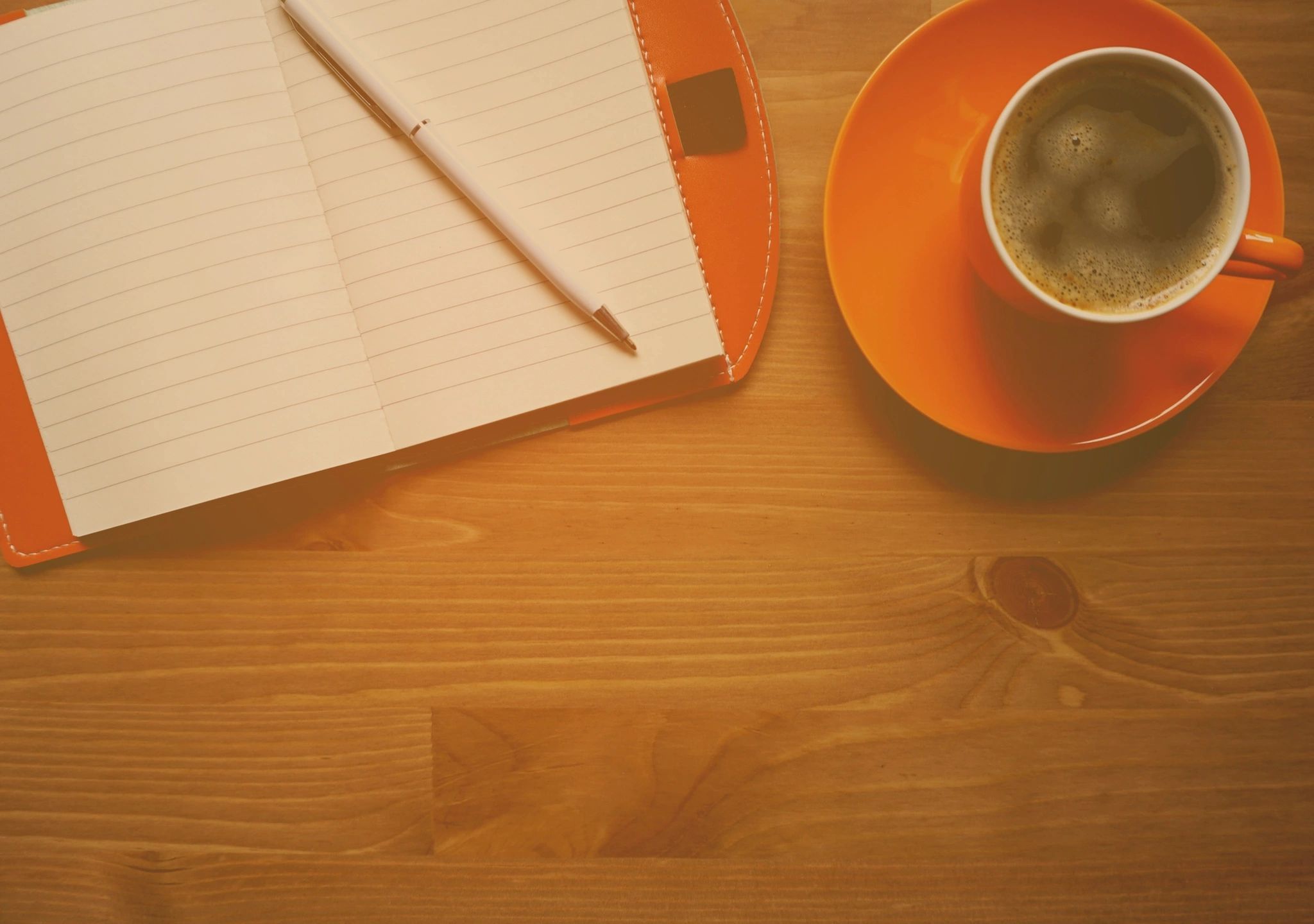 Overhead photo of notebook, pen, and cup of coffee to depict writing.